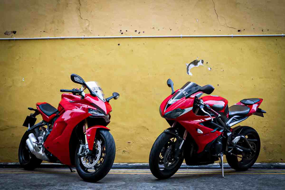 Due moto da velocità rosse parcheggiate davanti a un muro