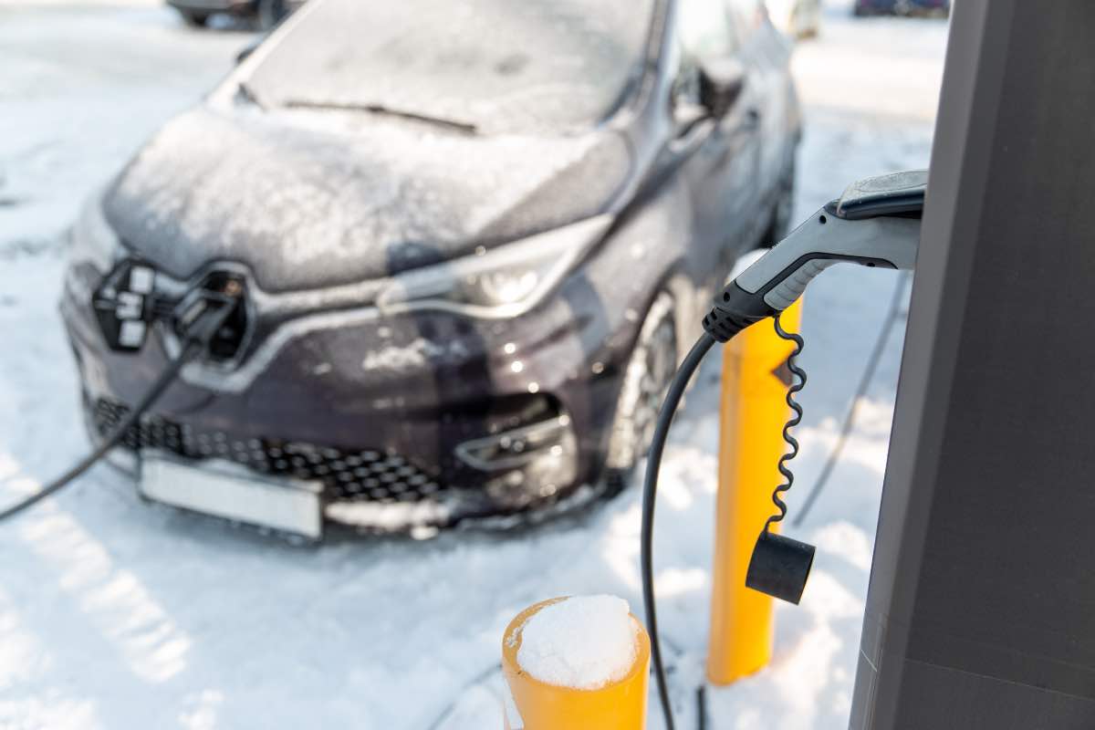 Un'auto elettrica sotto carica durante una nevicata