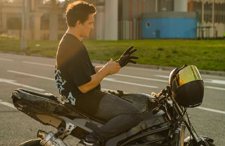 Uomo si mette i guanti da moto prima di guidare